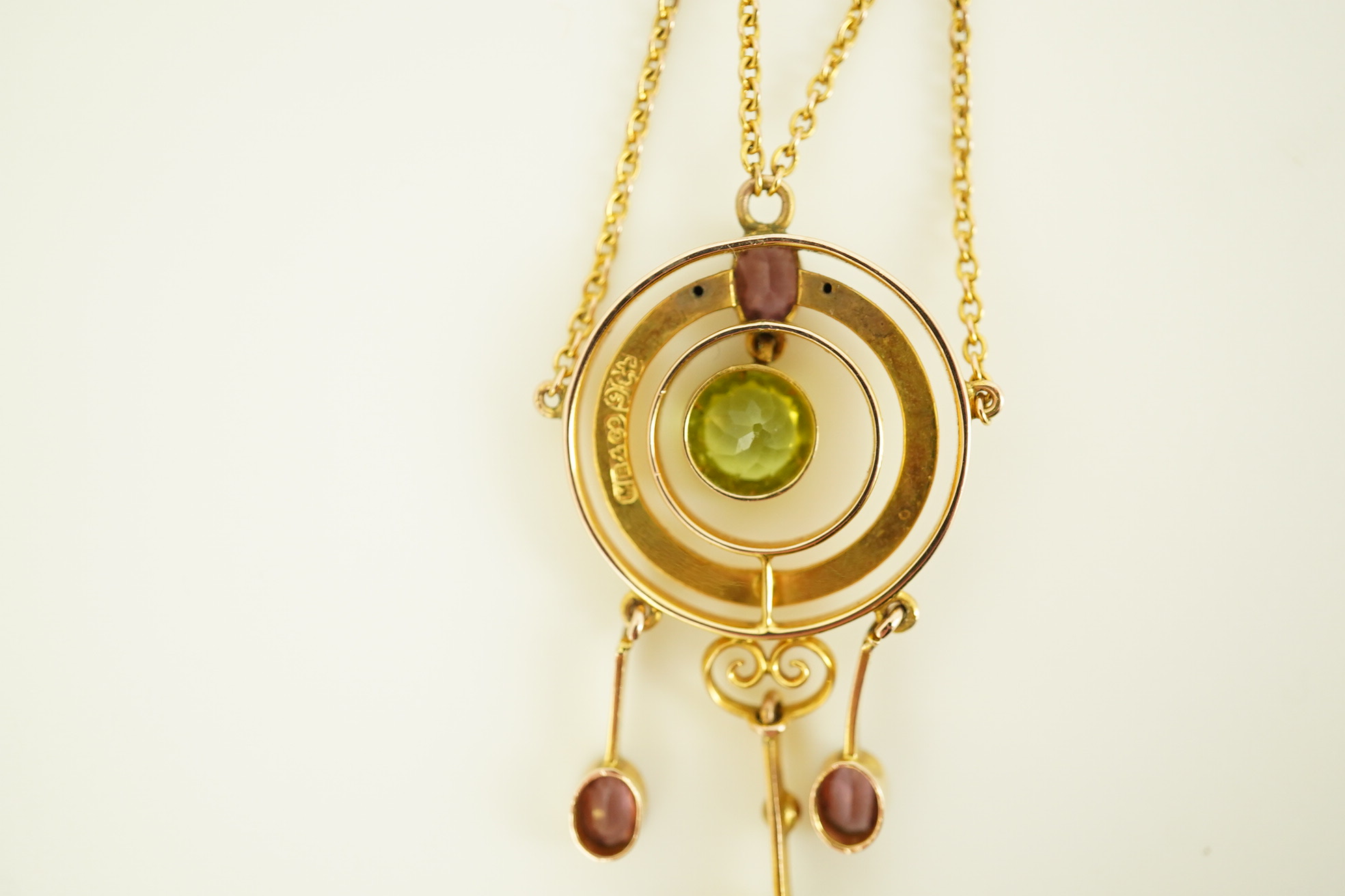 An Edwardian 9ct gold, peridot and garnet set drop pendant necklace, by Murrle Bennett & Co